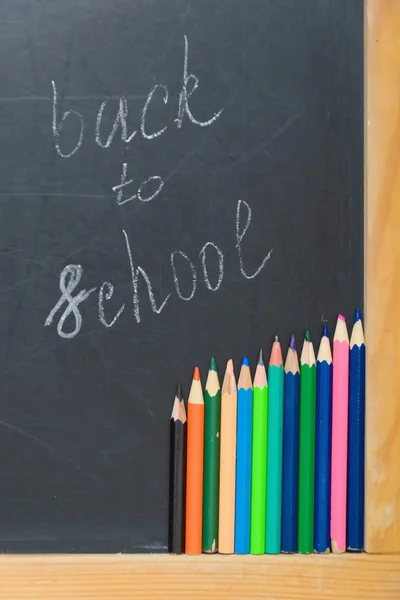 Colorful pencils on a black board. School concept
