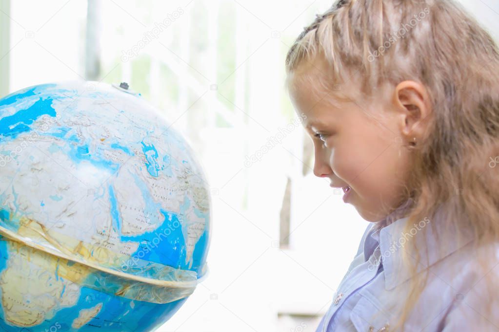 School girls look at globe at geography lesson