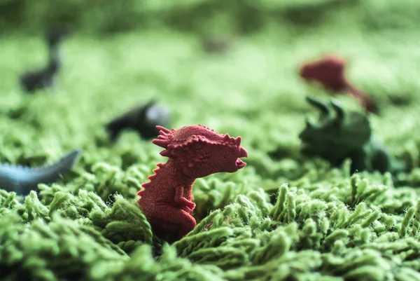 Hračky dinosauři ve vysoké trávě miniaturní divoký život Stock Snímky