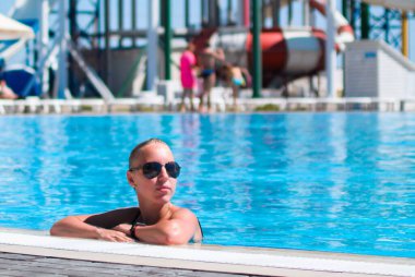 Aqua Park 'taki havuzda dinlenen beyaz sarışın, yaz tatili.