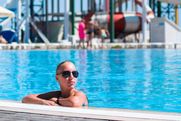 Aqua Park 'taki havuzda dinlenen beyaz sarışın, yaz tatili.