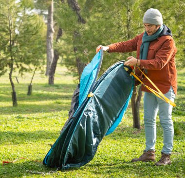Ormanda kamp çadırı kuran adam dışarıda eğleniyor.