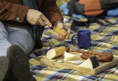 Yürüyüşçü peynir, sosis, ekmek ve kahveyle pikniğin tadını çıkarıyor.