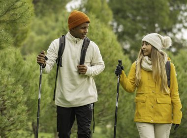 Yürüyüş direkleri ve sırt çantaları kullanarak sonbahar mevsiminde ormanda yürüyüş yapmaktan hoşlanan çeşitli yürüyüşçülerin portresi