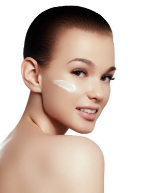 Güzel kız onun yüzüne cilt bakımı için biraz krema uygulamak. Gençlik ve cilt bakım kavramı. Kadın güzellik yüz portre sağlıklı cilt ile beyaz izole. Mükemmelsin yüzü ile spa kadın portre