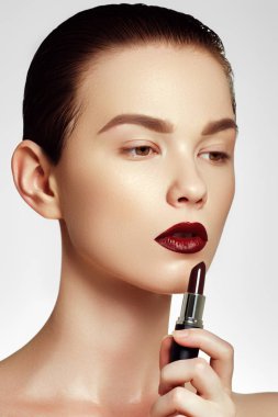 Kozmetik ve makyaj. Mükemmel dudak makyaj. Moda ve güzellik kavramı. Güzel genç kadın şarap ruj. Koyu kırmızı renkli pomad esmer modeliyle. Ruj uygulama manken