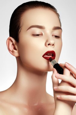 Kozmetik ve makyaj. Mükemmel dudak makyaj. Ruj uygulayarak bir modeldir. Güzel genç kadın şarap ruj. Modelin yüzü koyu kırmızı renkli merhem ile. Güzellik kavramı