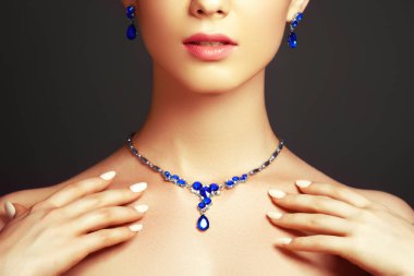 Takı ile zarif şık kadın. Safir bir kolye ile güzel bir kadın. Güzellik genç model gri bir arka plan üzerinde elmas bir kolye ile. Takı ve aksesuar. Güzellik ve moda kavramı