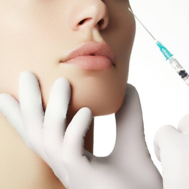 Genç kadın kozmetik enjeksiyon getting portresi. Tatlı güzel kadının yüzüne enjeksiyon alır. Dolgu enjeksiyonları. Dudak büyütme. Güzel mükemmel dudaklar