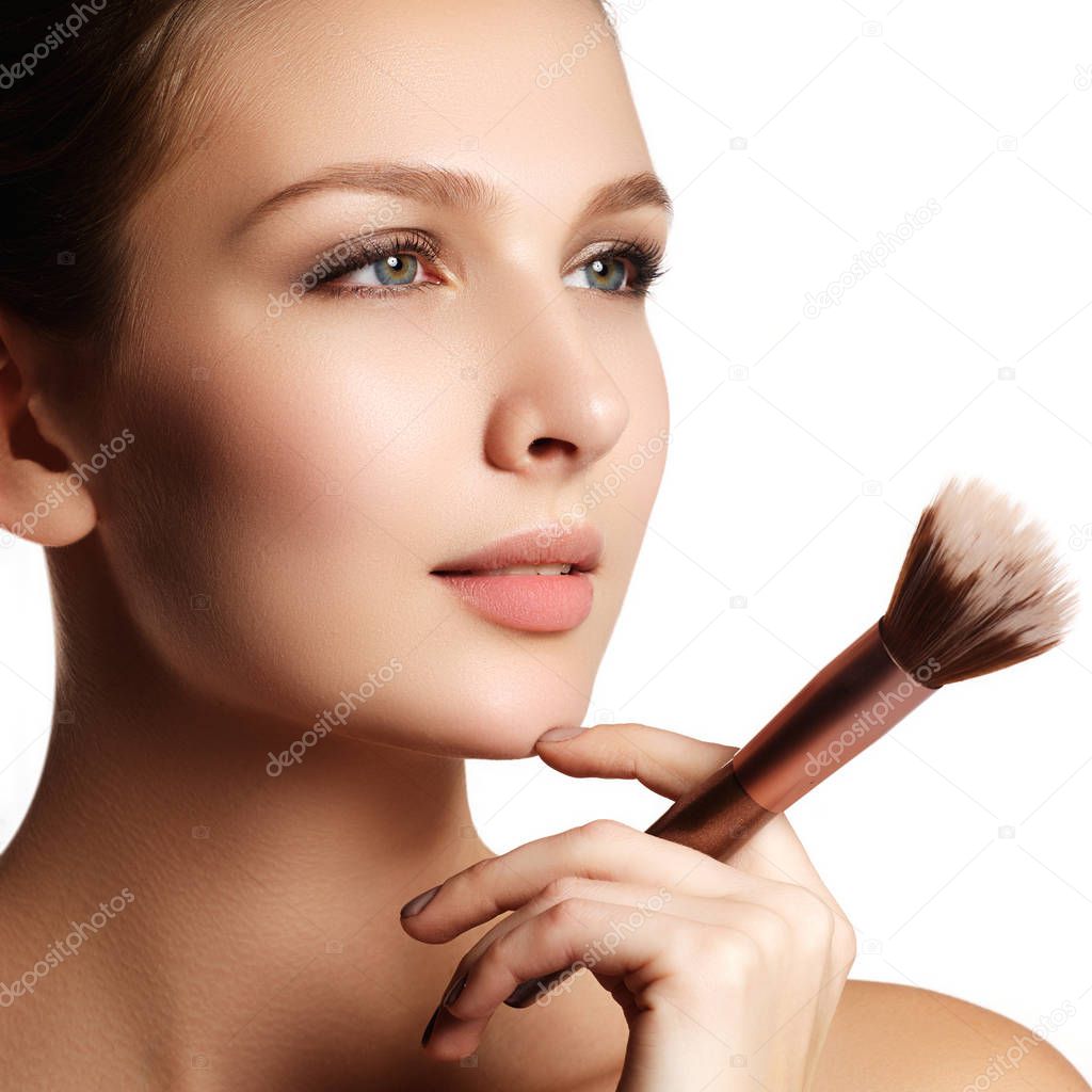 Beauty model with makeup brush. Bright make-up for brunette woman with blue eyes. Beautiful face. Perfect Skin. Applying makeup