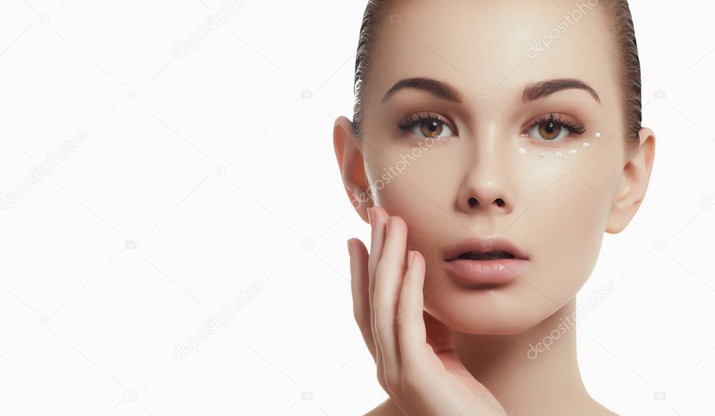 Beautiful girl applying some cream to her face for skin care. Youth and skin care concept. Woman beauty face portrait isolated on white with healthy skin. Portrait spa woman with perfect face