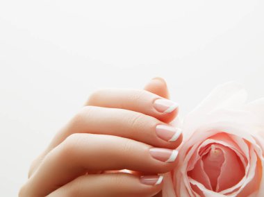 Manikür, eller spa güzel kadın eller, yumuşak deri, pembe gül çiçek yaprakları ile güzel tırnaklar. Eller sağlıklı kadın. Güzellik Salonu. Güzellik bakımı. Erkek ile güzel Fransız manikür çivi