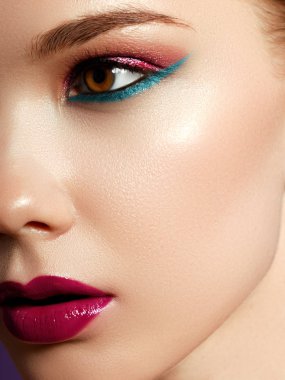 Kozmetik ürünleri. Neşeli genç kadının renkli makyaj ile kapatın. Kadın modeli ile menekşe arka plan üzerinde canlı makyaj Güzellik Portresi