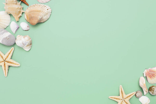 Flat lay. Top view. Frame of shells of various kinds on a green blue background. Seashells and starfish on a pastel background. Vacation concept