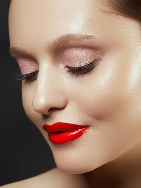 Muhteşem genç esmer kadın portresi. Mükemmel kaşlı, temiz makyajlı, kırmızı dudaklı, yüzüne dokunan güzel model kız. Parti için seksi bayan makyajı. Siyah arkaplanda izole