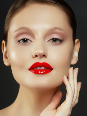 Muhteşem genç esmer kadın portresi. Mükemmel kaşlı, temiz makyajlı, kırmızı dudaklı, yüzüne dokunan güzel model kız. Parti için seksi bayan makyajı. Siyah arkaplanda izole