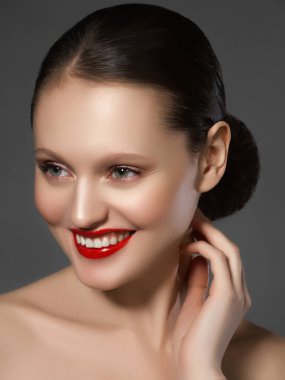 Muhteşem genç esmer kadın portresi. Mükemmel kaşlı, temiz makyajlı, kırmızı dudaklı, yüzüne dokunan güzel model kız. Parti için seksi bayan makyajı. Siyah arkaplanda izole