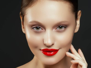 Muhteşem genç esmer kadın portresi. Mükemmel kaşlı, temiz makyajlı, kırmızı dudaklı, yüzüne dokunan güzel model kız. Parti için seksi bayan makyajı. Siyah arkaplanda izole