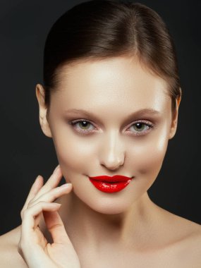 Muhteşem genç esmer kadın portresi. Mükemmel kaşlı, temiz makyajlı, kırmızı dudaklı, yüzüne dokunan güzel model kız. Parti için seksi bayan makyajı. Siyah arkaplanda izole