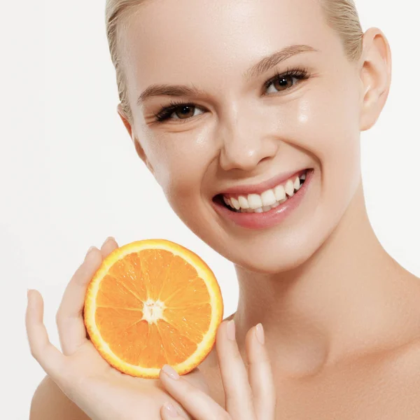 Chica sonriente con frutas frescas. Belleza modelo toma jugosas naranjas. Chica alegre con pecas. El concepto de una dieta saludable. Maquillaje profesional. Rebanada naranja — Foto de Stock