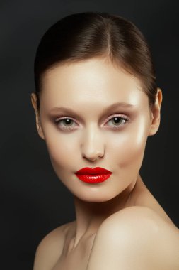 Muhteşem genç esmer kadın portresi. Mükemmel kaşlı, temiz makyajlı, kırmızı dudaklı, yüzüne dokunan güzel model kız. Parti için seksi bayan makyajı. Siyah arkaplanda izole