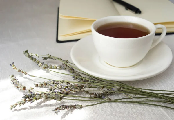 Csendélet egy csésze teával, egy jegyzetfüzettel és vadvirágokkal.. — Stock Fotó