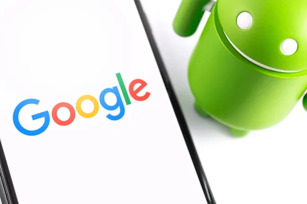 Primer plano Google Android figura y teléfono inteligente —  Fotos de Stock