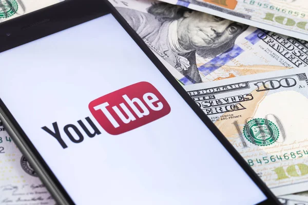 Billets de banque dollars et logo YouTube sur le smartphone écran. Toi. — Photo