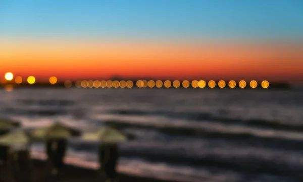 Vervaag de parasols en lichten op het nacht strand — Stockfoto