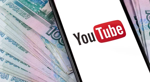 YouTube logó a képernyőn okostelefon és orosz pénz, rubelt. — Stock Fotó