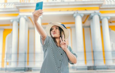 Güzel turist kız Granada katedralinde selfie çekiyor. Şapkalı genç bir turist meydanda selfie çekiyor. Selfie ve tatil kavramı