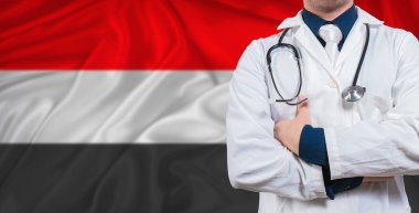 Yemen bayrağında steteskoplu bir erkek doktor. Doktor, Yemen bayrağında steteskop tutuyor.