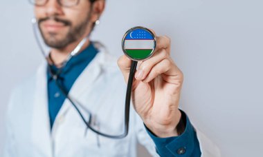 Özbekistan bayrağıyla steteskop tutan doktor. Özbekistan sağlık ve bakım kavramı, Özbekistan bayrağı steteskopta
