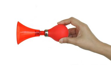 Asyalı kadının eli beyaz bir arka plan üzerinde kırmızı rüzgar boynuzu esiyor.