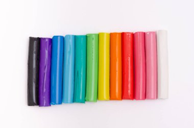 Beyaz arkaplanda yığılmış çok renkli modelleme killeri.