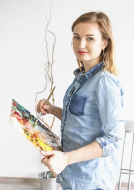 Kız sanatçı boya üreten bir paletle bir sanat atölyesi resim çizer. Paletleri ve şövale, yaratıcı ruh hali