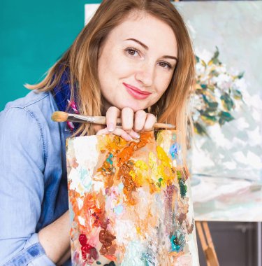 bir kız ressam portre renkli bir sanat stüdyosu resimlerinde bir palet ile. Düşünceli sanatçı, yaratıcı ruh hali