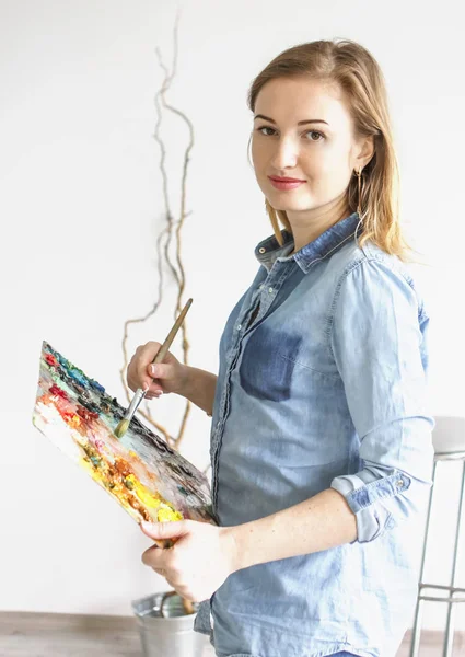 Kız sanatçı boya üreten bir paletle bir sanat atölyesi resim çizer. Paletleri ve şövale, yaratıcı ruh hali