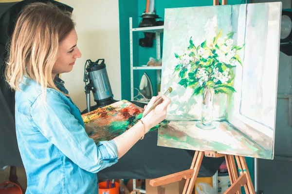 Kız sanatçı boya üreten bir paletle bir sanat atölyesi resim çizer. Paletleri ve şövale, yaratıcı ruh hali