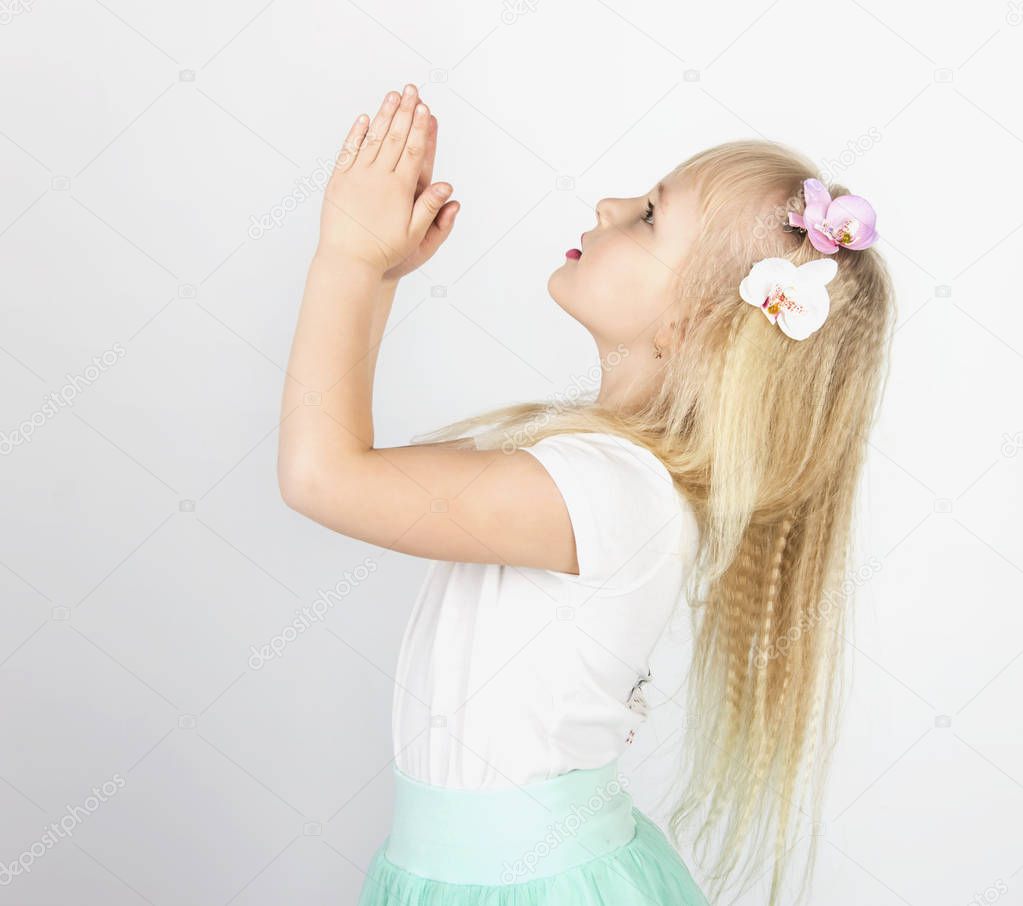 little blond girl folded her hands in prayer to God. A little angel. Side view
