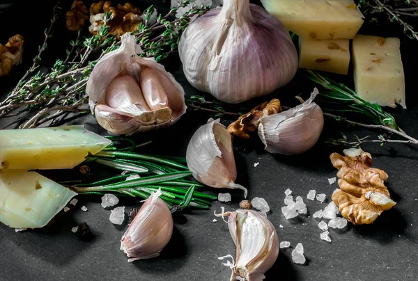 Garlic. Garlic on a black background. Nuts, cheese, rosemary and