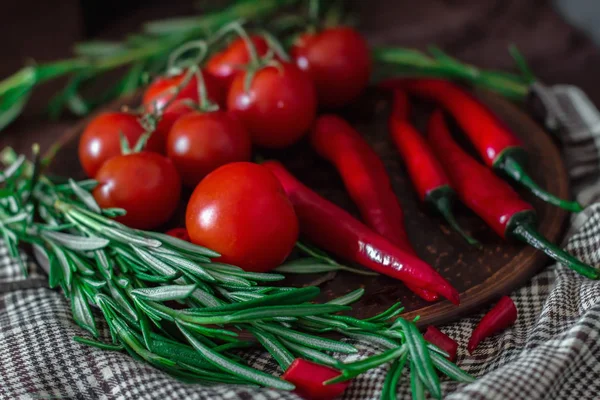 Färska körsbärstomater, kvistar rosmarin och chilipeppar på en — Stockfoto
