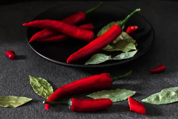 Chilipeppar och lagerblad på en mörk sten bakgrund. Örter och — Stockfoto