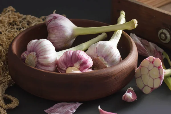 Fresh garlic. Kind of garlic in a clay plate sitting against a d — Stock Photo, Image