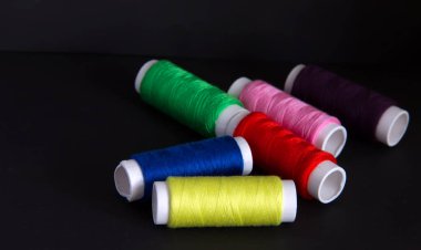 Koyu bir arka plan üzerinde dikiş için parlak renkli iplikler. İğne oyası