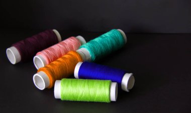 Koyu bir arka plan üzerinde dikiş için parlak renkli iplikler. İğne oyası