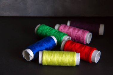 Koyu bir arka plan üzerinde dikiş için parlak renkli iplikler. İğne oyası