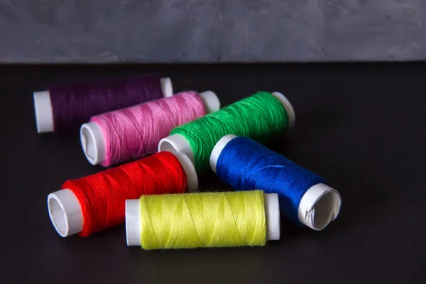 Bright colored threads for sewing on a dark background. Needlewo