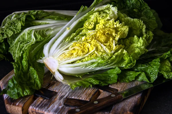 Kubis Cina segar dalam potongan pada latar belakang kayu gelap. Diet Stok Gambar