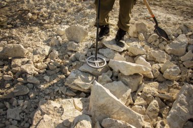 Tarihi değerleri araştıran metal dedektörlü bir adam.